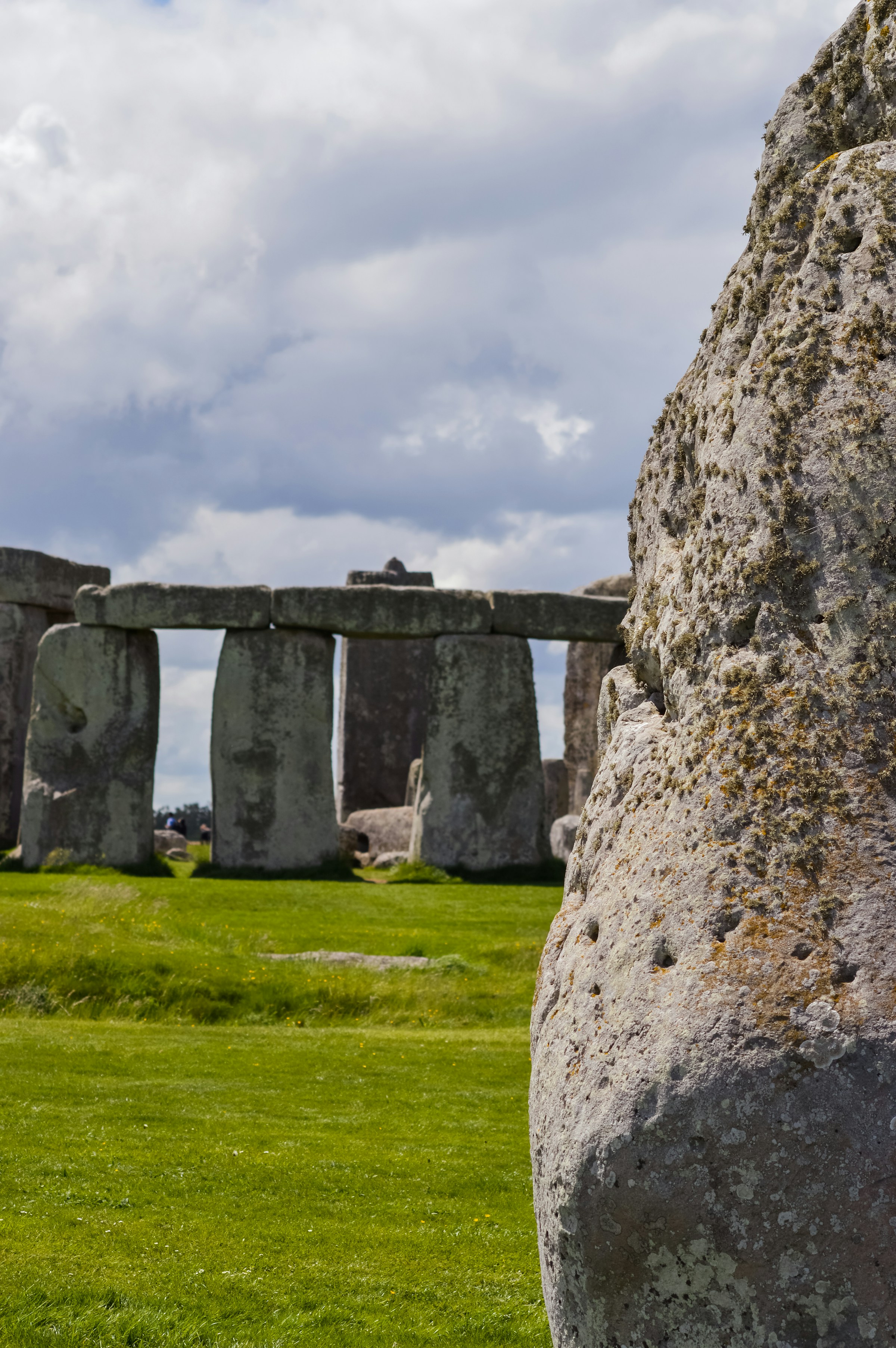 Standing stones at Stonehenge seen across open grass, with the visitor path in the distance